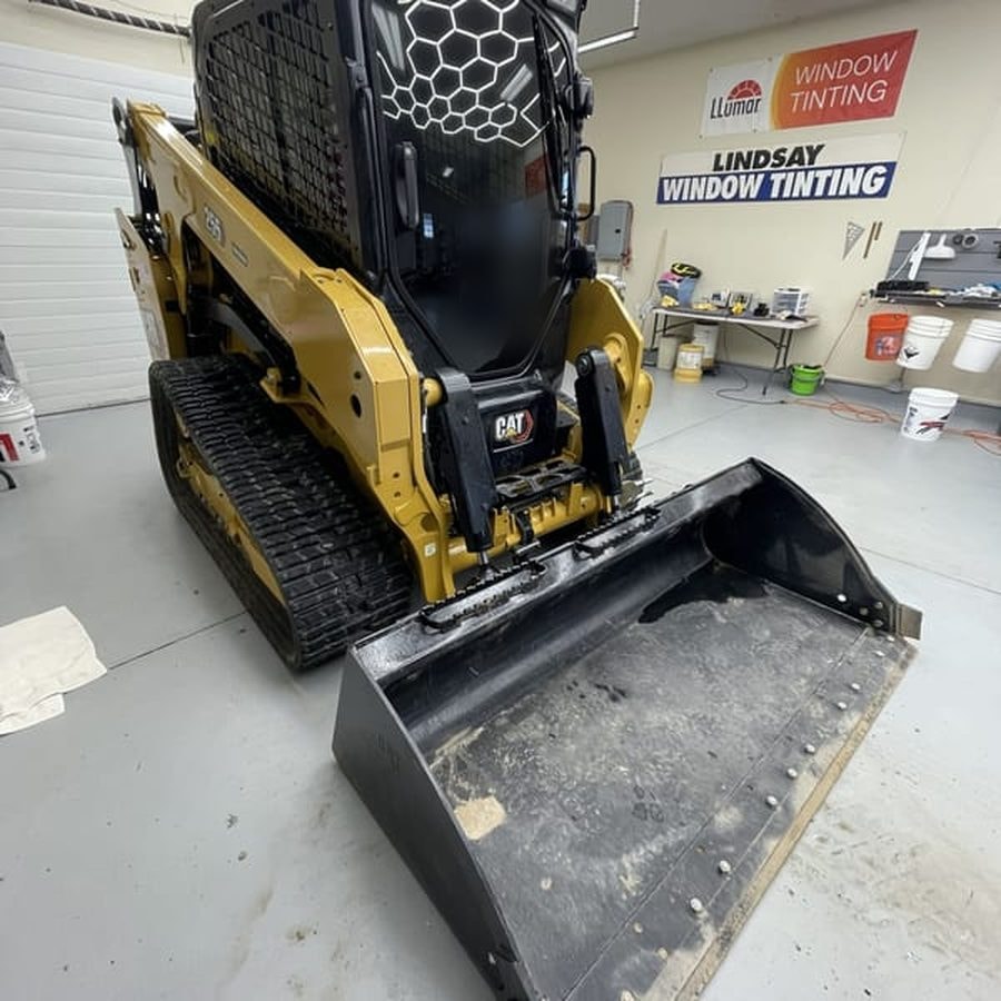 Cat compact track loader with tinted cab glass inside the Lindsay Window Tinting shop in Rochester, NY